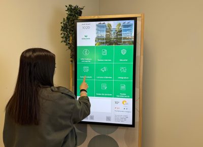 Collaboratrice utilisant une borne digitale RH dans les espaces de l'entreprise.